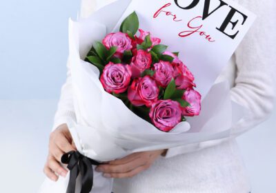 10 purple roses with ruscus in a white wrap with note 'Love For You'