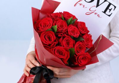 10 red roses with ruscus in a white wrap with note 'Love for You'