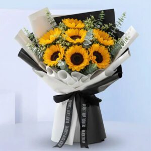 A vibrant sunflower bouquet wrapped in white paper and tied with a black ribbon.