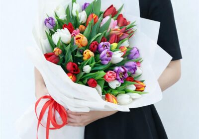 Hand bouquet of 50 colourful mixed tulips in assorted soft and vibrant colors wrapped neatly for gifting.