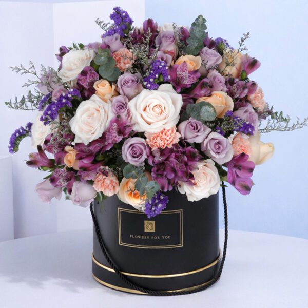 blossom-fusion-round-box Black round floral box featuring a fusion of purple flowers arranged neatly with lush greenery in a compact, elegant design.