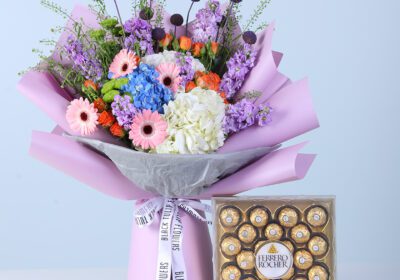 Cheerful Bloom Celebration Box with Ferrero featuring mixed vibrant and pastel flowers with chocolates arranged in a modern gift box