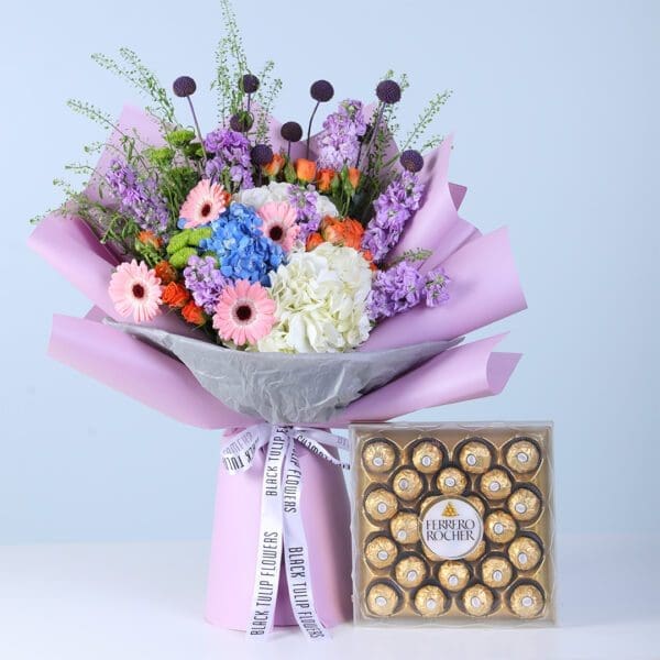 cheerful-bloom-celebration-box-with-ferrero-rocher-24-pcs Cheerful Bloom Celebration Box with Ferrero featuring mixed vibrant and pastel flowers with chocolates arranged in a modern gift box