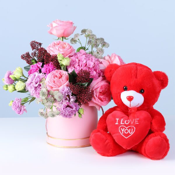 Elegant Pastel Blooms with Teddy featuring pink roses, hydrangea, lisianthus, carnations, and a teddy arranged in a pink hatbox for gifting