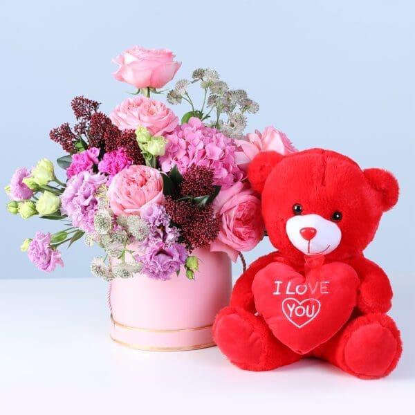 elegant-pastel-blooms-with-teddy Elegant Pastel Blooms with Teddy featuring pink roses, hydrangea, lisianthus, carnations, and a teddy arranged in a pink hatbox for gifting