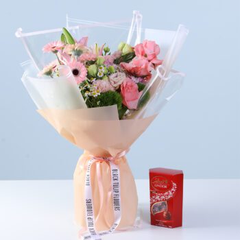 Graceful Pink Celebration Bouquet with Lindt featuring pink gerberas, roses, lilies, hydrangea, and seasonal flowers arranged with chocolate for gifting