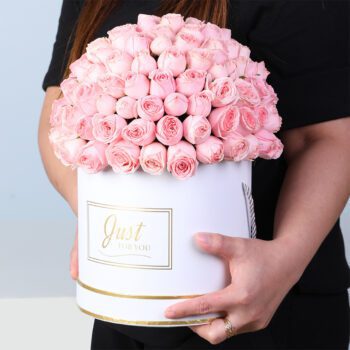 White round box containing fresh light pink spray roses, elegantly arranged