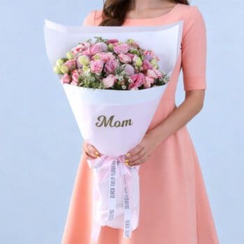 Soft pink floral hand bouquet featuring lisianthus, roses, and fresh greens wrapped in white satin.