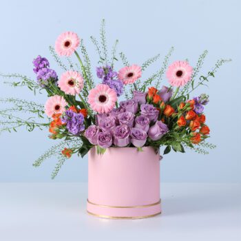 Floral arrangement with deep and light flowers in a pink gift box