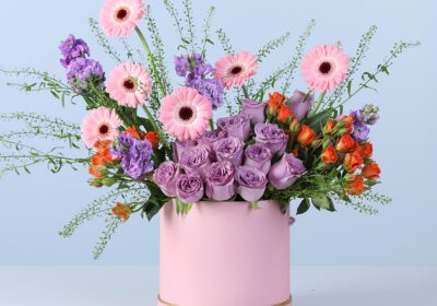 Floral arrangement with deep and light flowers in a pink gift box