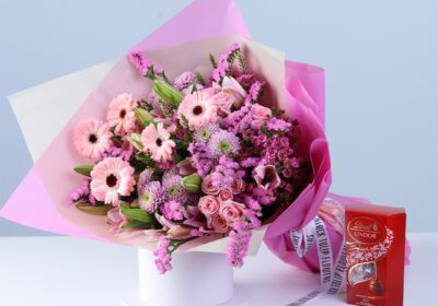 Pink Bloom Bouquet Lindt Box Combo featuring mixed flowers like gerberas, lilies, baby roses, and chrysanthemums arranged with Lindt chocolate for gifting