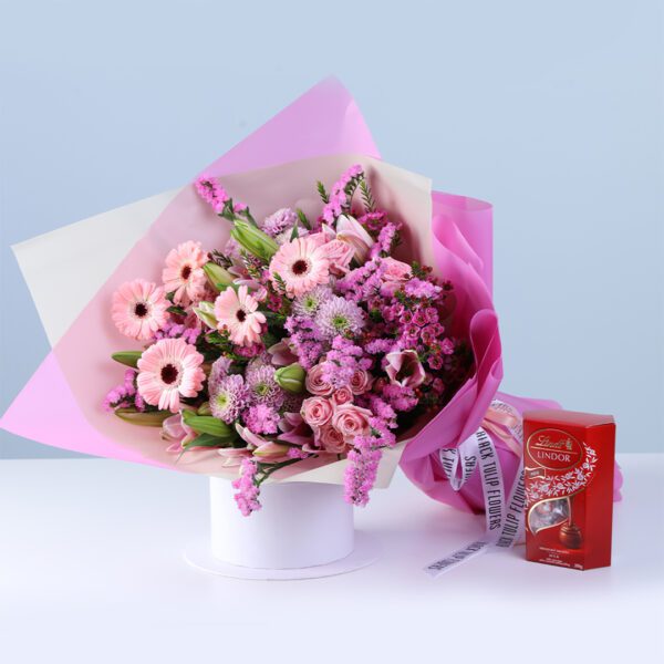 Pink Bloom Bouquet Lindt Box Combo featuring mixed flowers like gerberas, lilies, baby roses, and chrysanthemums arranged with Lindt chocolate for gifting
