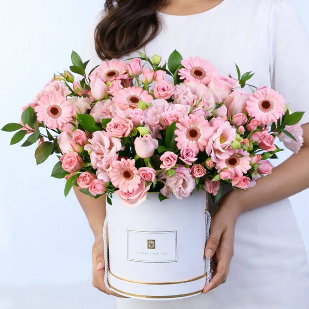 Elegant pink roses and gerberas floral arrangement in a white gift box with fresh greenery