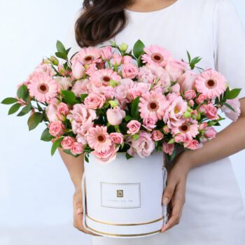 Elegant pink roses and gerberas floral arrangement in a white gift box with fresh greenery