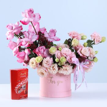 Premium Rose Lisianthus Lindt Combo featuring pink roses, lisianthus, purple roses, skimmia, and Lindt chocolate arranged in a pastel hatbox
