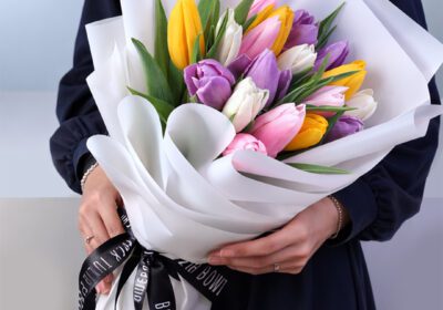 Colorful mixed tulip bouquet wrapped in white paper with a premium ribbon, featuring vibrant fresh tulips