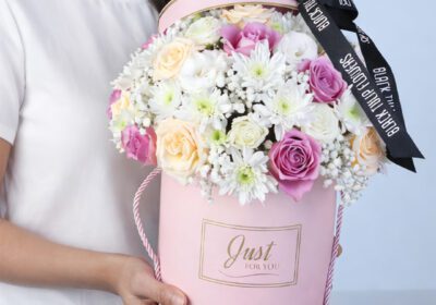 Royal Peach Lavender Flower Box featuring purple roses, peach roses, lisianthus, chrysanthemums, and gypsophila arranged in a round pink box