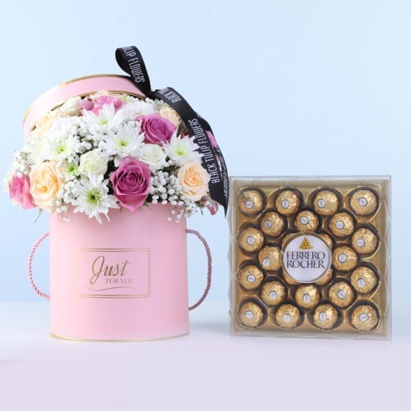 signature-peach-bloom-ferrero-24-pcs-combo_001 Signature Peach Bloom Ferrero 24 Pcs Combo featuring purple roses, peach roses, lisianthus, chrysanthemums, and Ferrero chocolates arranged in a round pink box