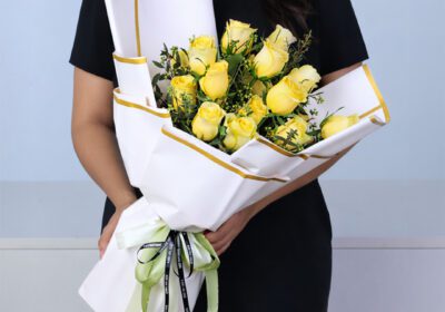 Hand bouquet of fresh yellow roses elegantly wrapped in white paper