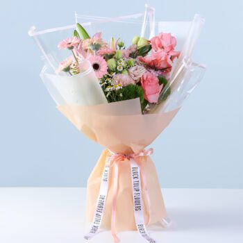 Soft Pink Bliss Bouquet with pink gerberas, roses, lilies, hydrangea, and seasonal flowers wrapped in peach for gifting