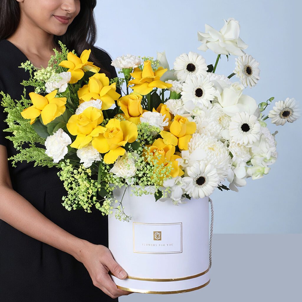 Sunlit Elegance Mixed Flower Box featuring yellow roses, white roses, carnations, gerberas, orchids, and fillers arranged beautifully for gifting and décor