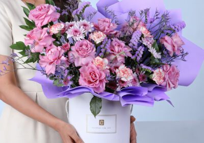 Violet Garden Floral Box featuring purple roses, bi-color carnations, chrysanthemums, and filler flowers arranged in an elegant luxury bouquet