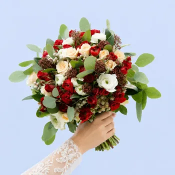 Blush Scarlet Bridal Bouquet featuring red and white ranunculus, spray roses, skimmia, brunia, and populas leaves in an editorial-style wedding arrangement