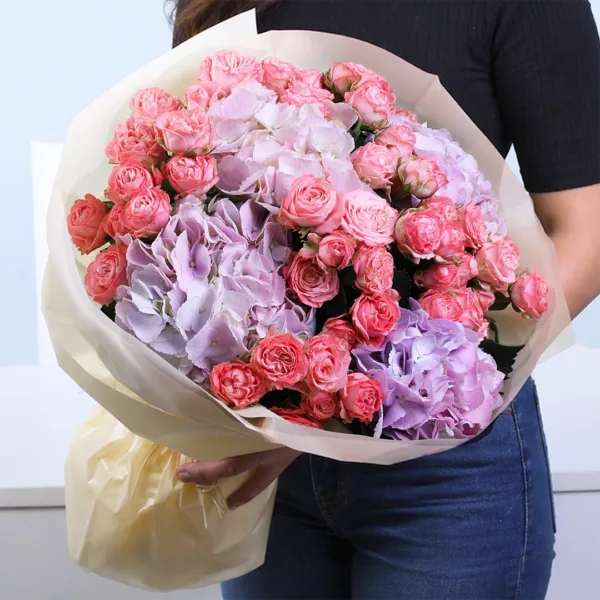Pastel Symphony Bouquet featuring orange spray roses and purple hydrangea arranged in a vibrant and elegant floral design