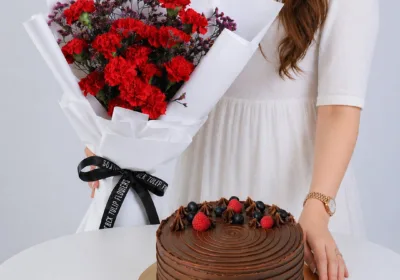 Red Bliss Cake Combo featuring red carnations, wax flowers, and a 1kg double chocolate cake for gifting and celebrations